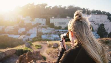 Woman in black jacket taking photo of city during daytime