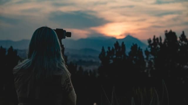 Landscape photo of a camera woman at sunset